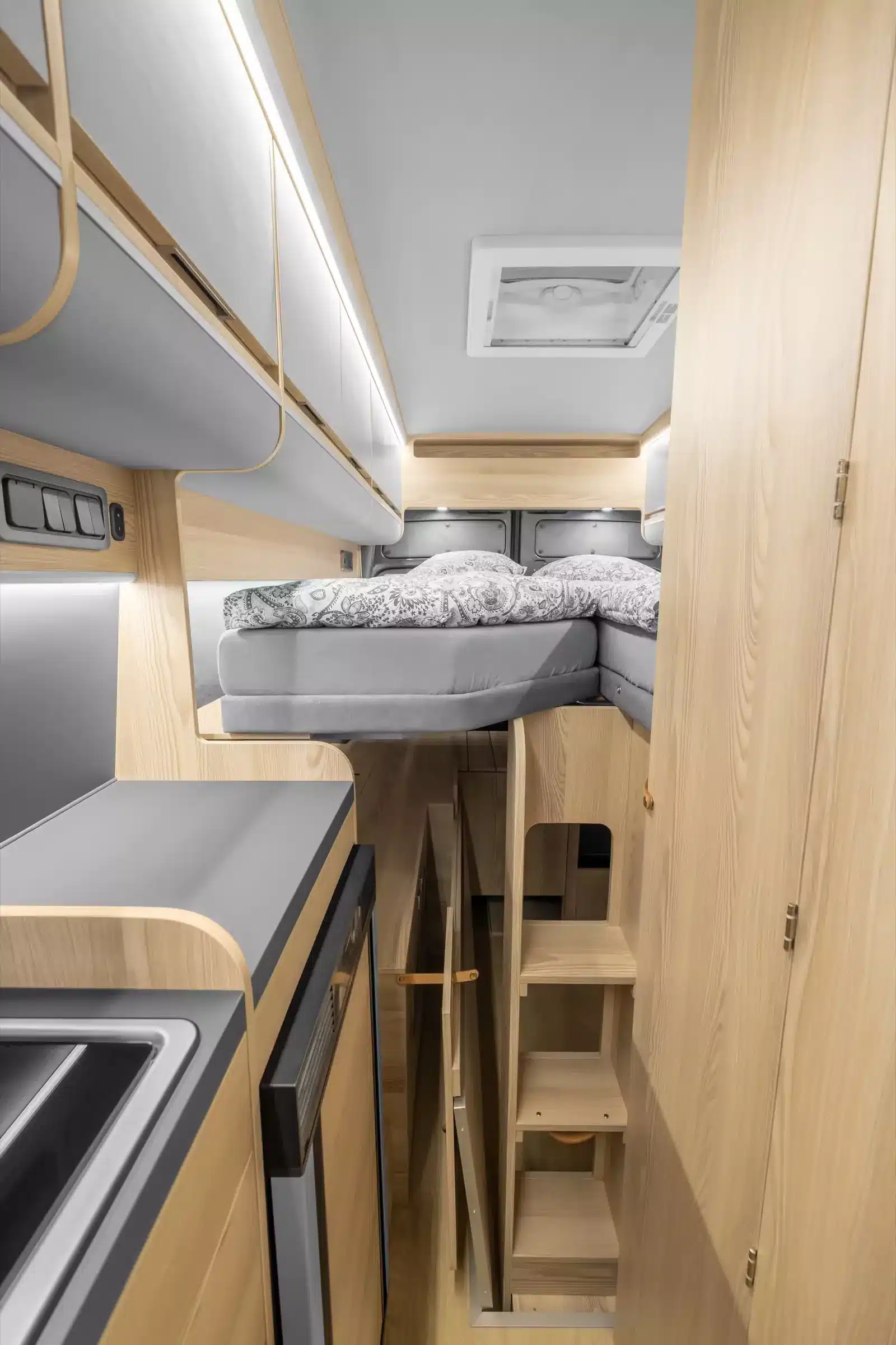 Innenansicht des Affinity M Three Campervans mit höhenverstellbarem Bett und Stauflächen im Heck