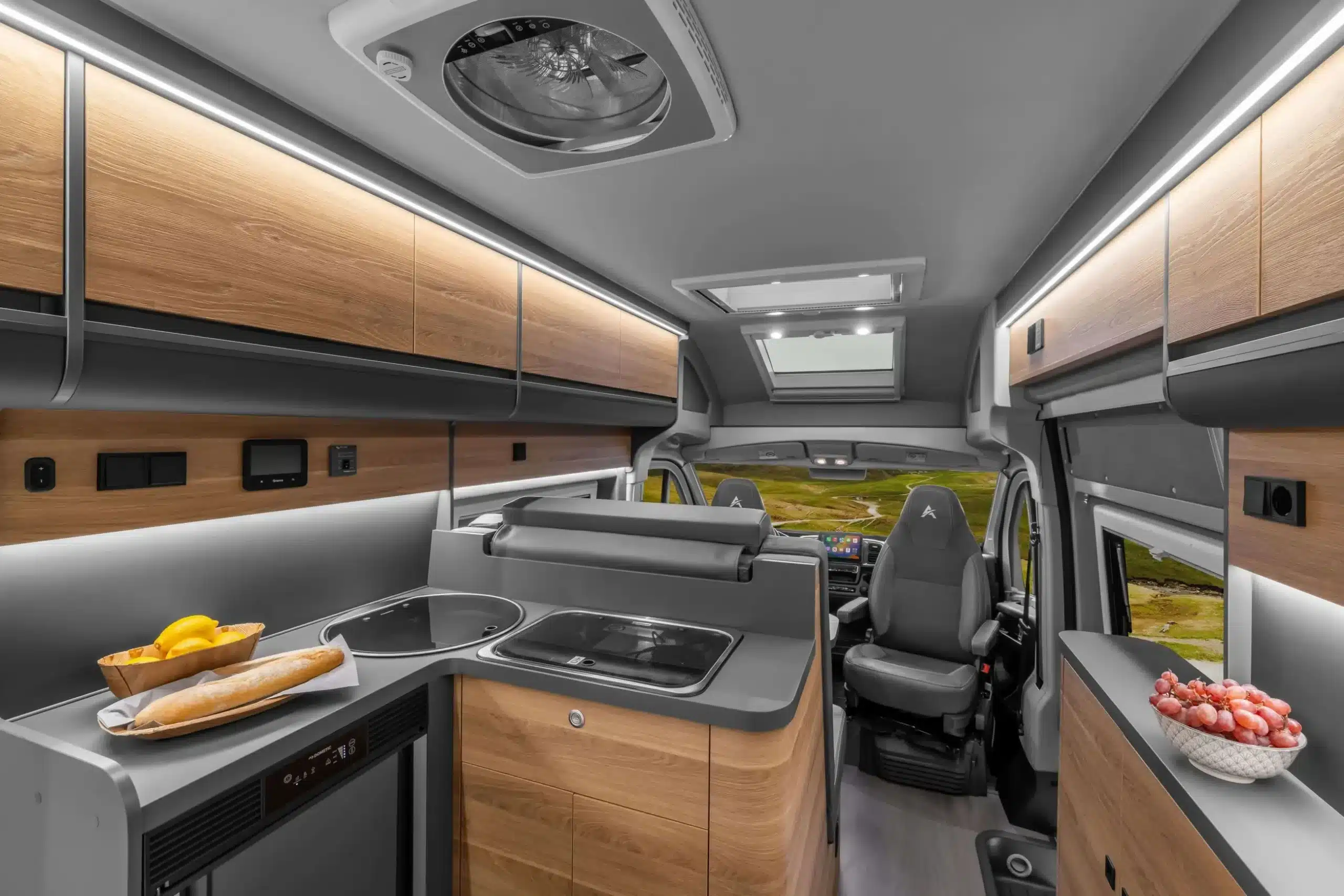 L-förmige Küche und Wohnbereich im AFFINITY ONE Kastenwagen von vorn aufgenommen.