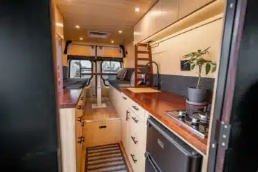 Individuell ausgebauter Camper-Innenraum mit Bambus, Küchenblock, Tisch und Sitzplätzen, Design inspiriert von japanischer Teehaus-Architektur