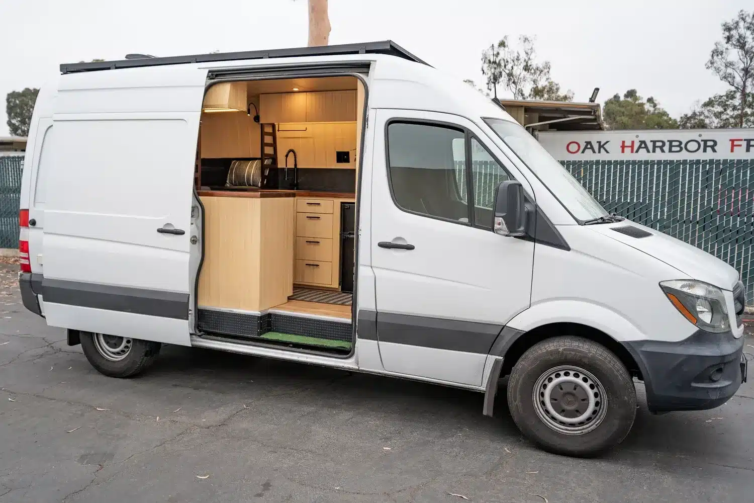 Seitliche Ansicht des individuell ausgebauten Campervans Appa von Vamonos Vans, mit geöffneter Tür und sichtbarer Bambus-Einrichtung.