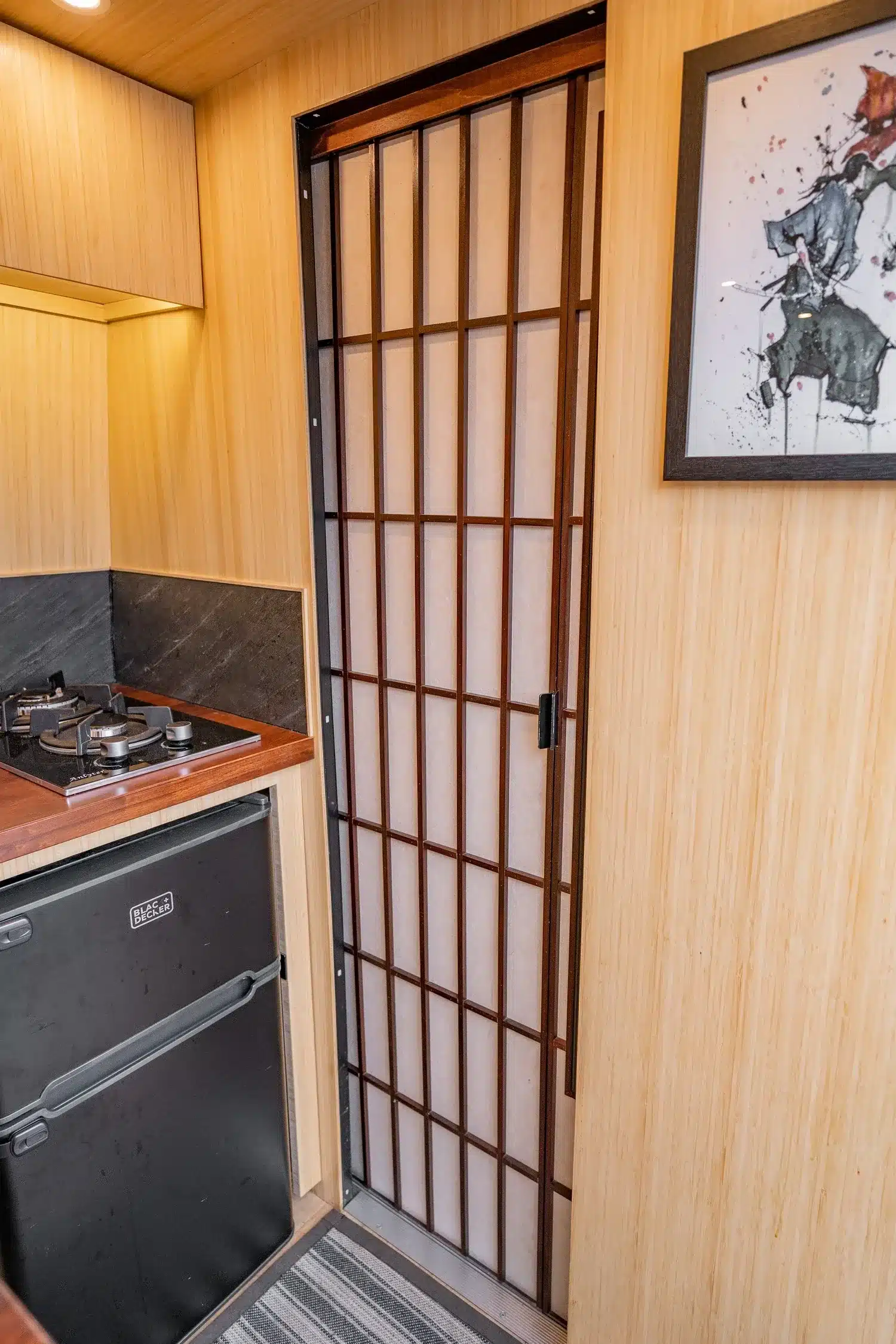 Innenaufnahme des Appa Campervans mit Kochfeld, Kühlschrank und Shoji-Schiebetür aus Bambus.