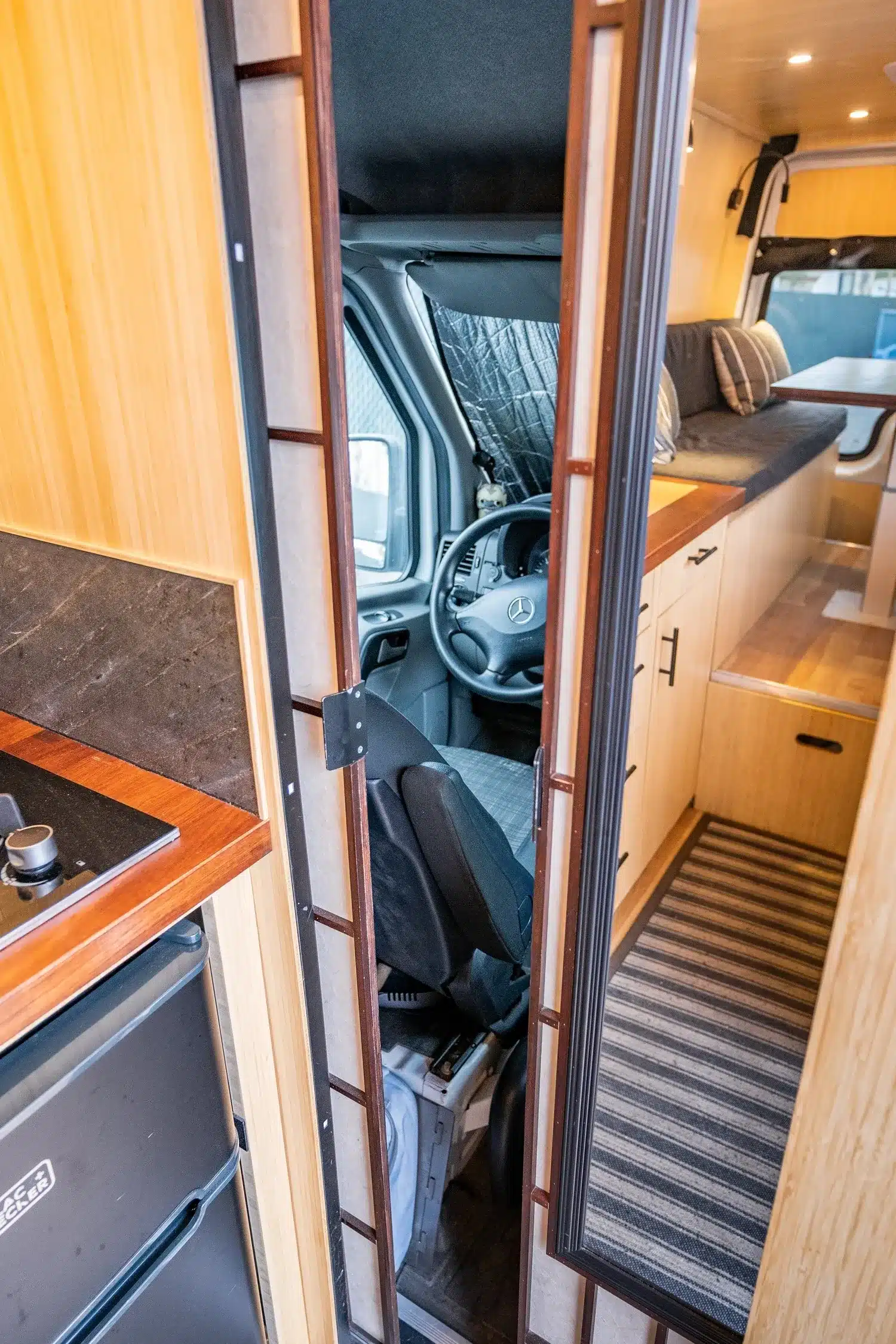 Innenraum des Appa Campervan mit Küche, Sitzbank und Zugang zum Fahrerhaus