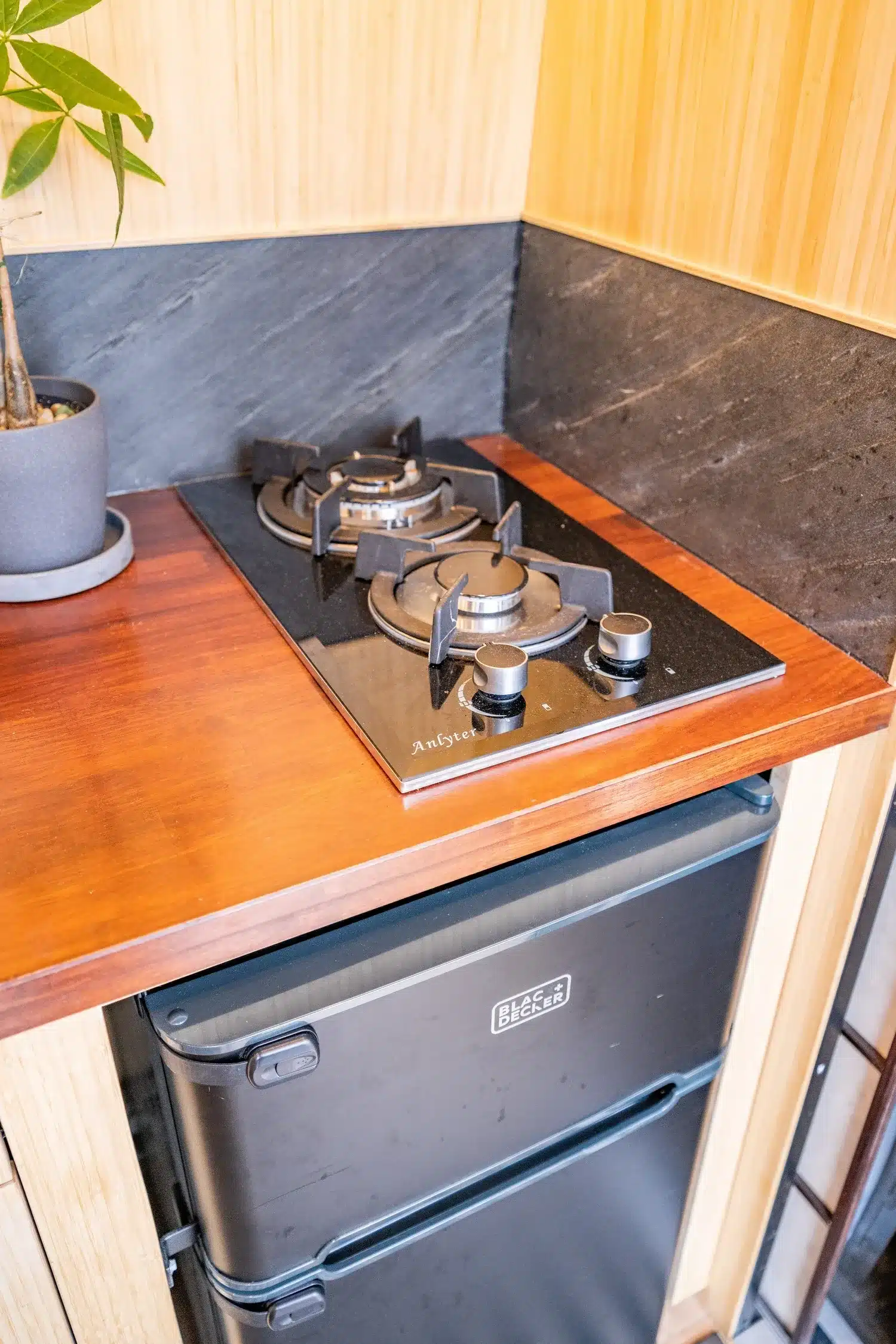 Gaskocher und Black+Decker Kühlschrank in der Küche des Appa Vans mit Bambusverkleidung und Schiefer-Fliesenspiegel.