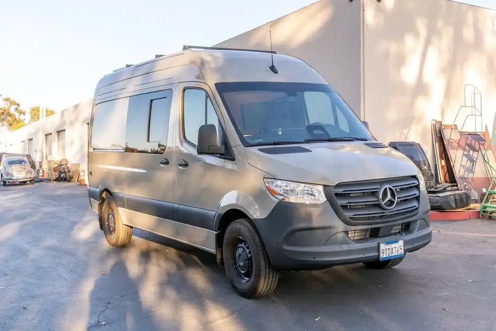 Der Base Camp 2 Campervan steht auf einem Mercedes Sprinter-Fahrgestell vor einer Halle.