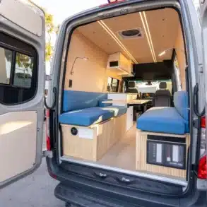 Blick in das Heck eines Base Camp 2 Vans mit modularer Sitzgruppe, Tisch, Stauraum und hellen Materialien