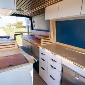 Blick in den modernen, modularen Innenraum eines Base Camp Campervans mit Küchenzeile, Sitzbank und viel Stauraum