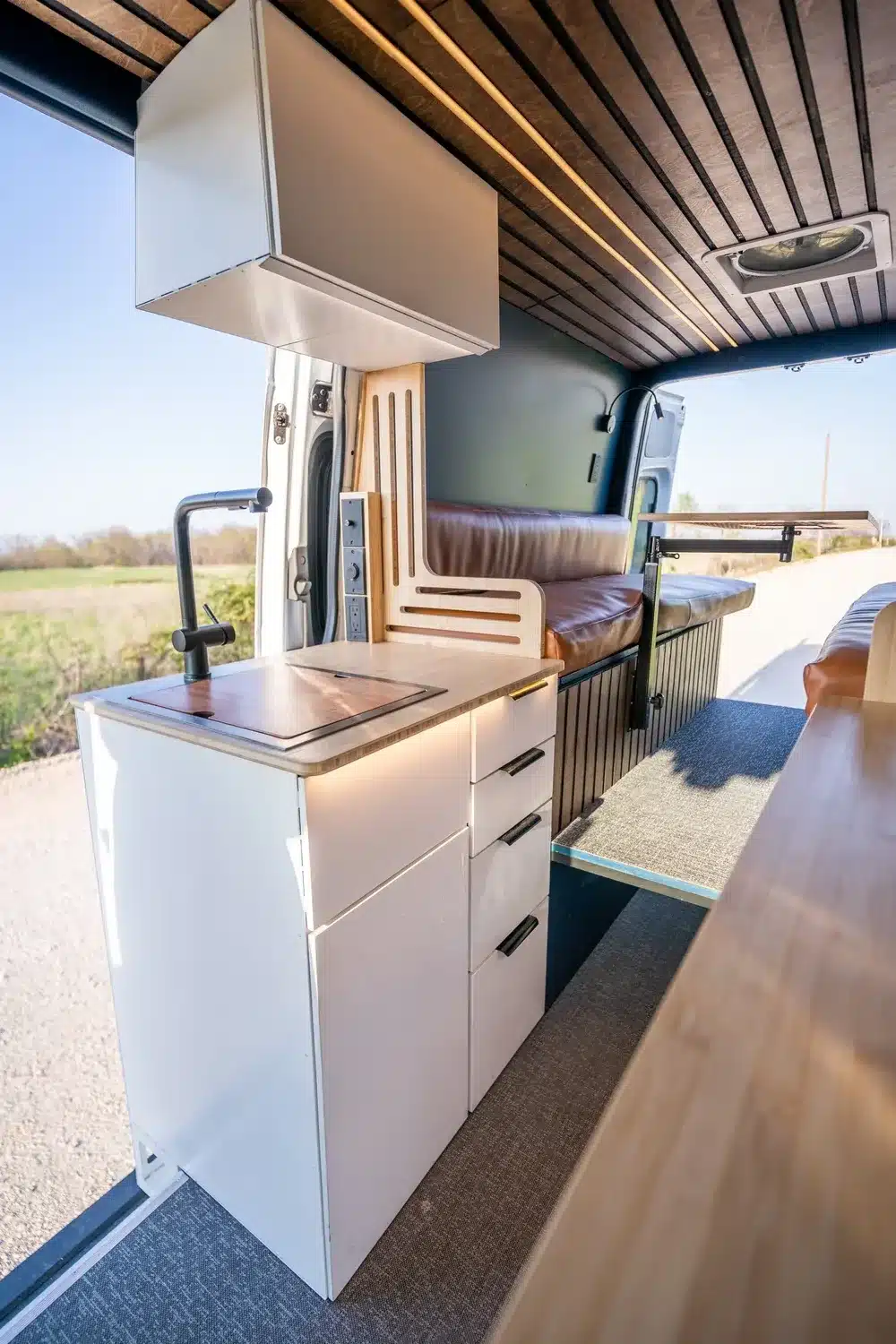 Innenansicht eines Campervans mit modularer Küchenzeile, Spüle und Sitzbereich von Vamonos Vans Base Camp.