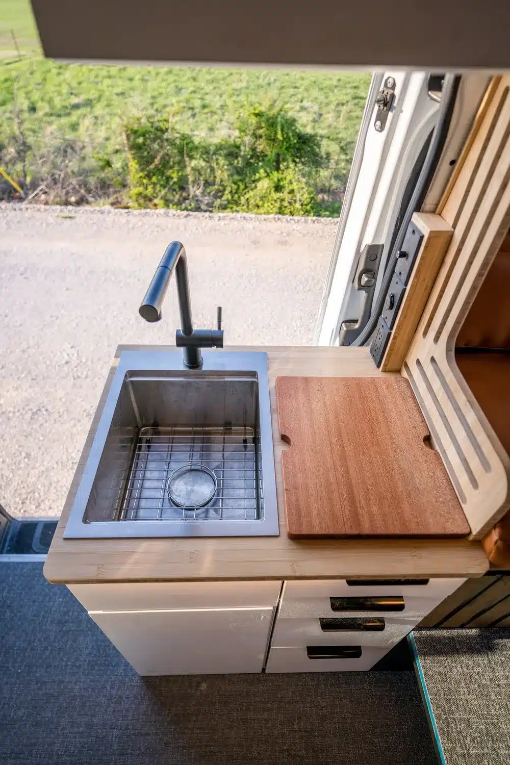 Küchenmodul mit Edelstahlspüle, Wasserhahn und Holzarbeitsfläche im Base Camp Vanlife-Ausbau