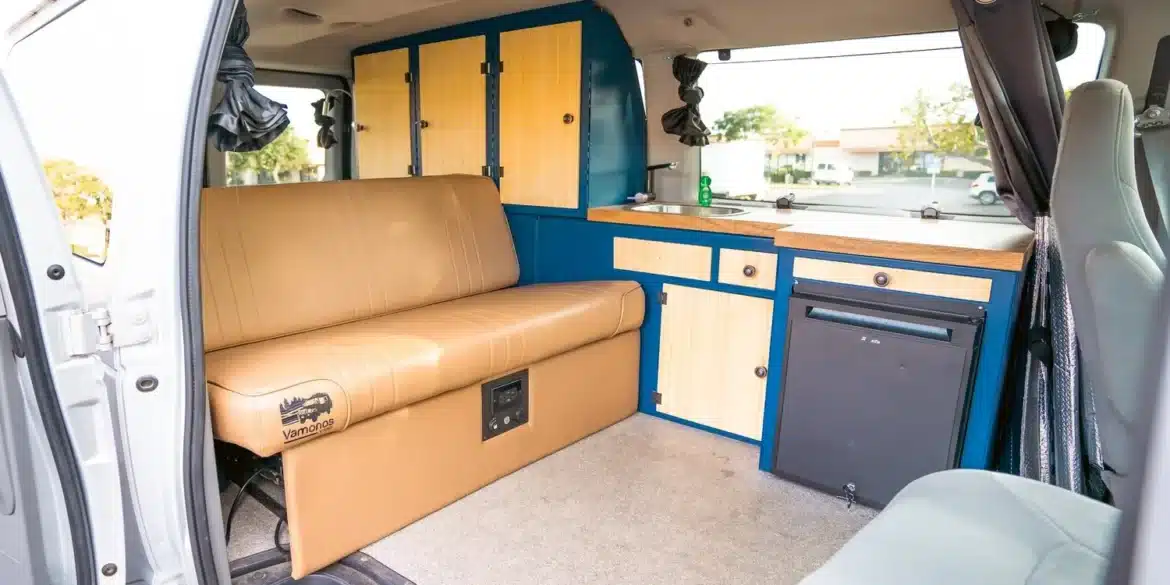 Modernisierter Innenraum eines Campervans mit blauen Aluminiummöbeln, Sitzbank und Küchenzeile