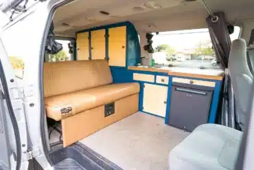 Modernisierter Innenraum eines Campervans mit blauen Aluminiummöbeln, Sitzbank und Küchenzeile
