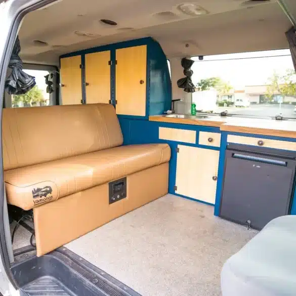 Modernisierter Innenraum eines Campervans mit blauen Aluminiummöbeln, Sitzbank und Küchenzeile