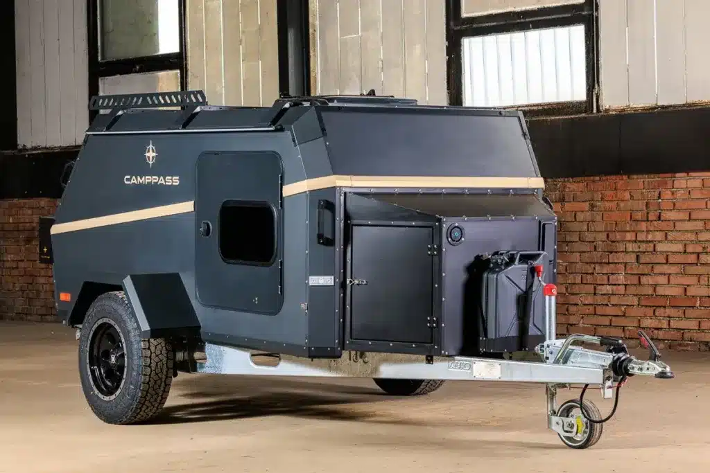 Seitenansicht eines Camppass CR400 Campinganhängers mit Offroad-Bereifung und Ausstattung, aufgenommen in einer Halle.