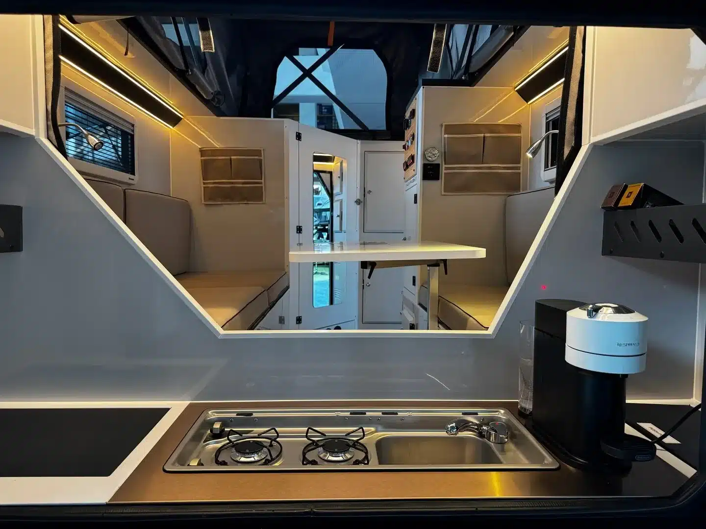 Kombinierte Außenküche mit Gasherd und Blick in den modern gestalteten Innenraum des Camppass CR455 Caravan