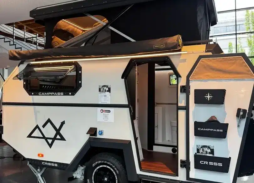 Camppass CR555 Offroad-Camper mit aufgeklapptem Dach und geöffneter Tür, Innenraum teilweise sichtbar.