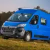 Blauer Citroën Jumper L2H2 Kastenwagen, geparkt auf einer Wiese vor Bäumen