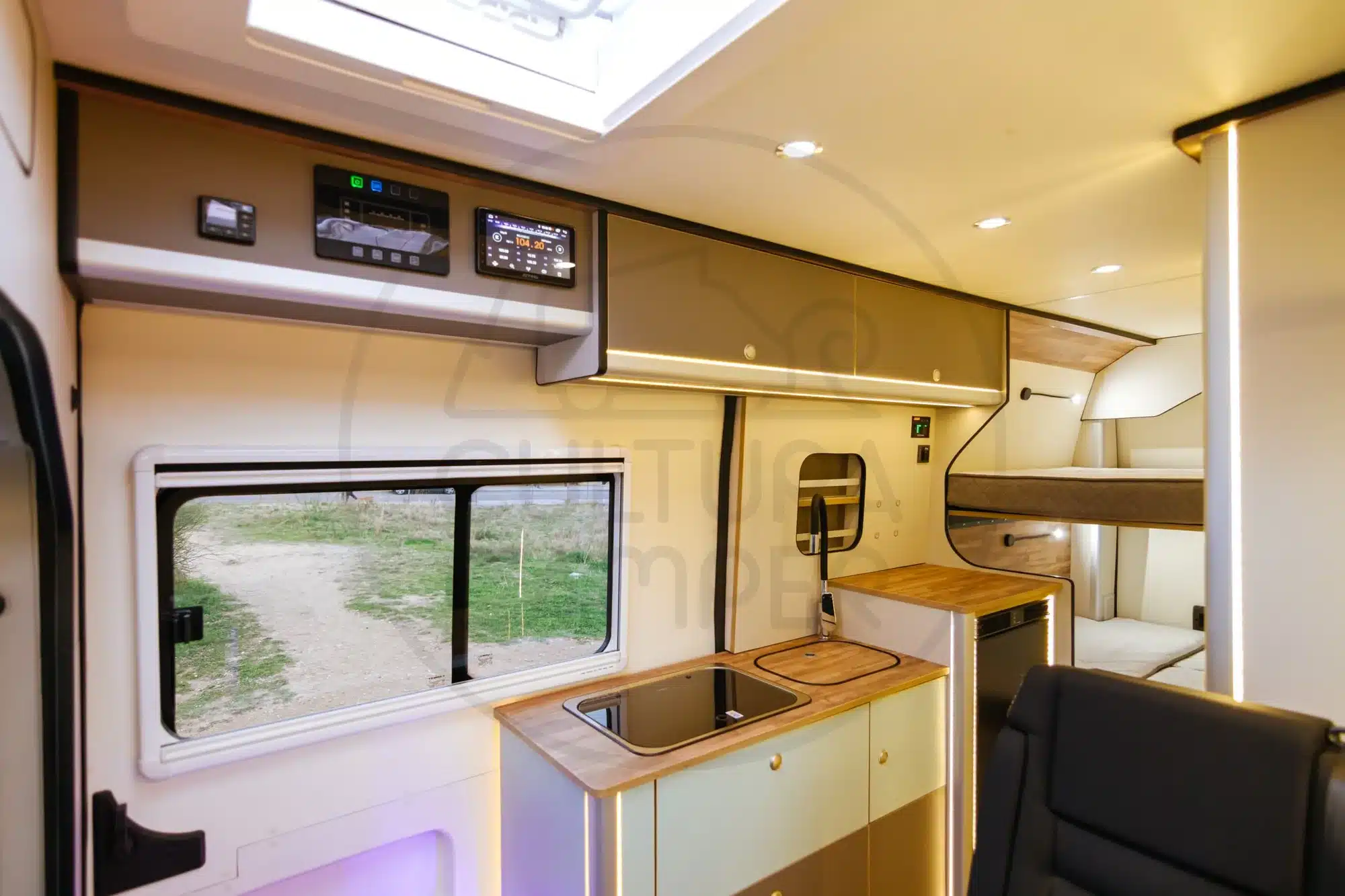 Innenansicht eines Citroën Jumper L3H2 Campers mit Küchenzeile, Steuerungspanel und Etagenbett