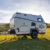 CR550i-Camping-Trailer von Camppass mit Offroad-Bereifung auf einer grünen Wiese bei Sonnenuntergang