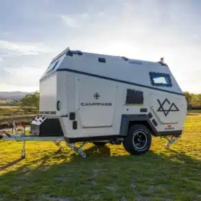 CR550i-Camping-Trailer von Camppass mit Offroad-Bereifung auf einer grünen Wiese bei Sonnenuntergang