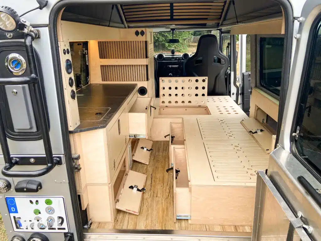 Innenansicht des ausgebauten Land Rover Defender 110 als Camper mit Möbelmodulen aus Holz