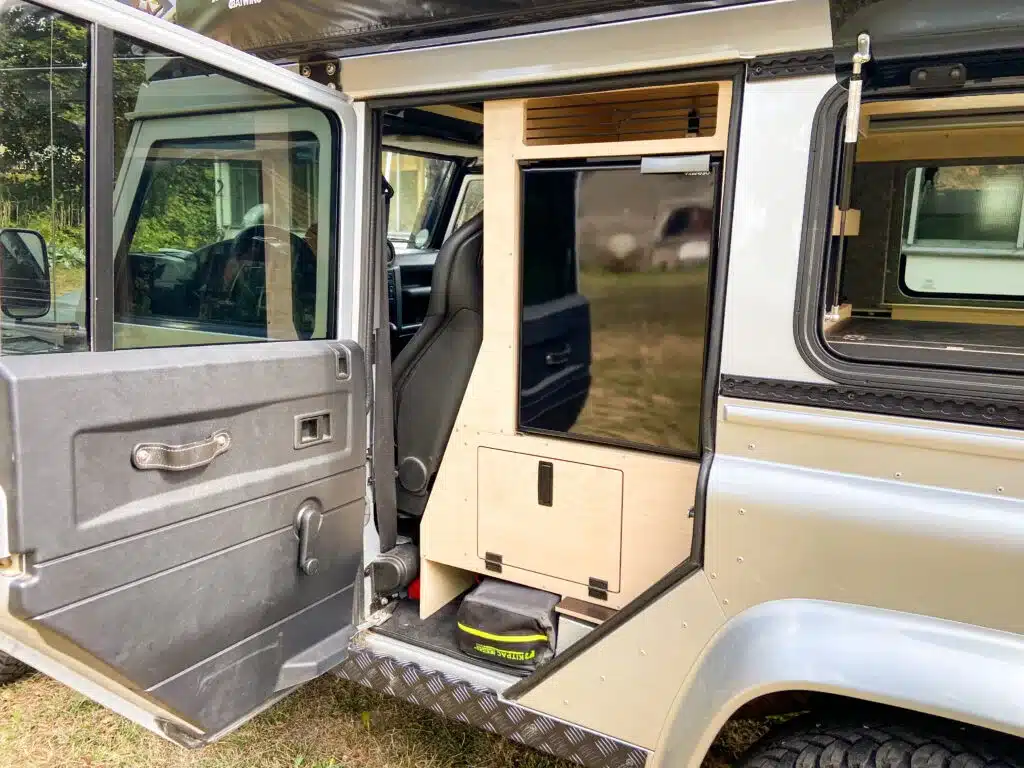 Innenausbau eines Land Rover Defender 110 mit seitlich geöffneter Tür, Hochschrank und Stauraum.