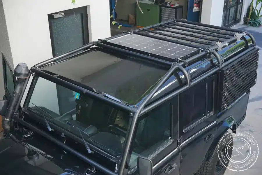 Solarmodul auf dem Dach eines Land Rover Defender 110 Station Wagon mit Überrollkäfig, Teil eines Camper-Ausbaus.