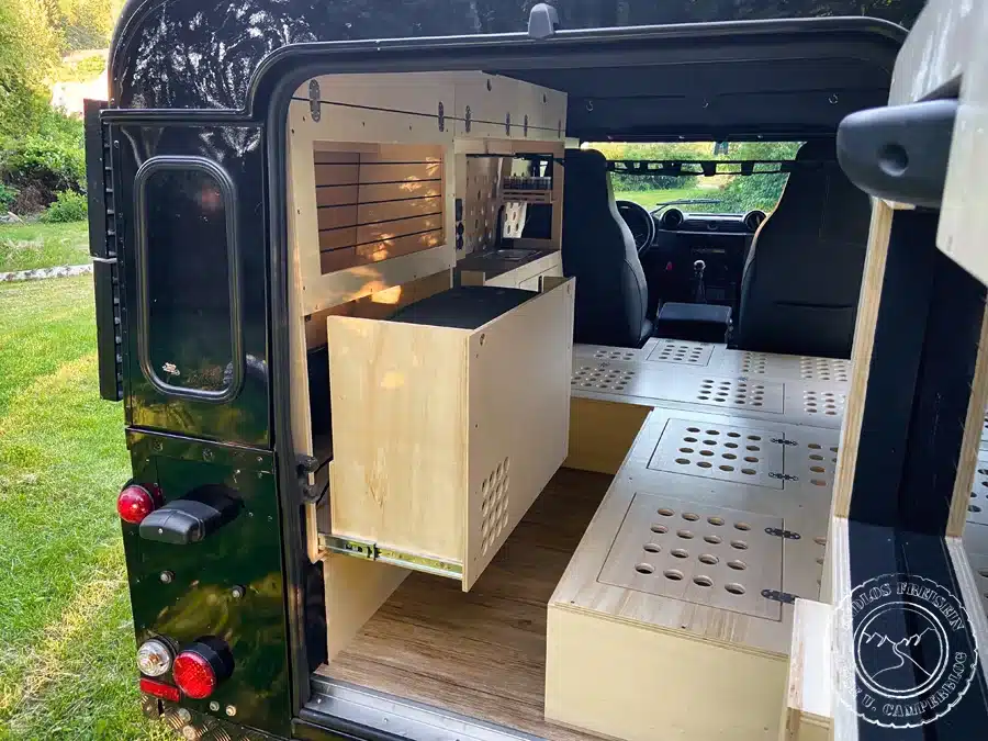 Innenausbau eines Land Rover Defender 110 SW mit maßgefertigten Möbeln, Stauraum und Küchenzeile zum Camper-Umbau.