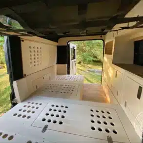 Innenraum eines umgebauten Land Rover Defender 110 SW als Reisemobil mit U-förmigem Grundriss, viel Stauraum und Küchenzeile