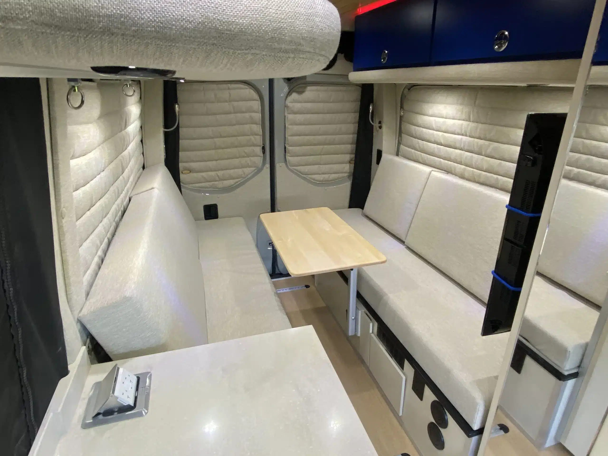 Innenansicht des Campervans The Bear mit gepolsterten Sitzbänken, Tisch und Stauraum