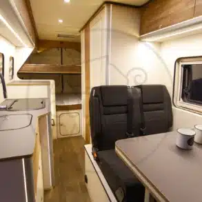 Innenraum eines Ducato L4H2 Campervans mit Küchenzeile, Sitzgruppe und Etagenbett, geeignet für Familienreisen und Vanlife mit Hunden.