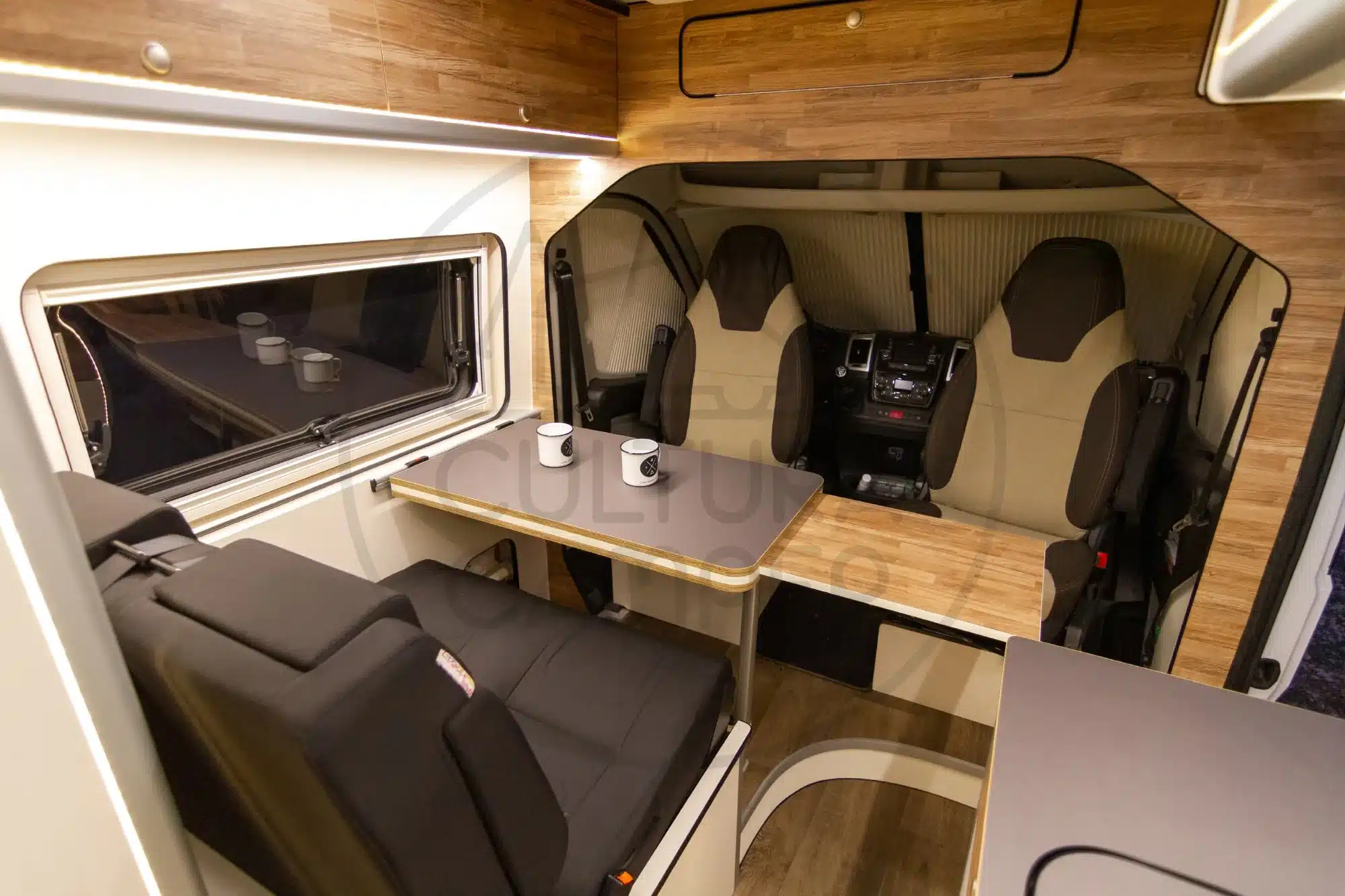 Sitzgruppe, Tisch und Fahrerhaus im modern ausgebauten Fiat Ducato L4H2 Campervan