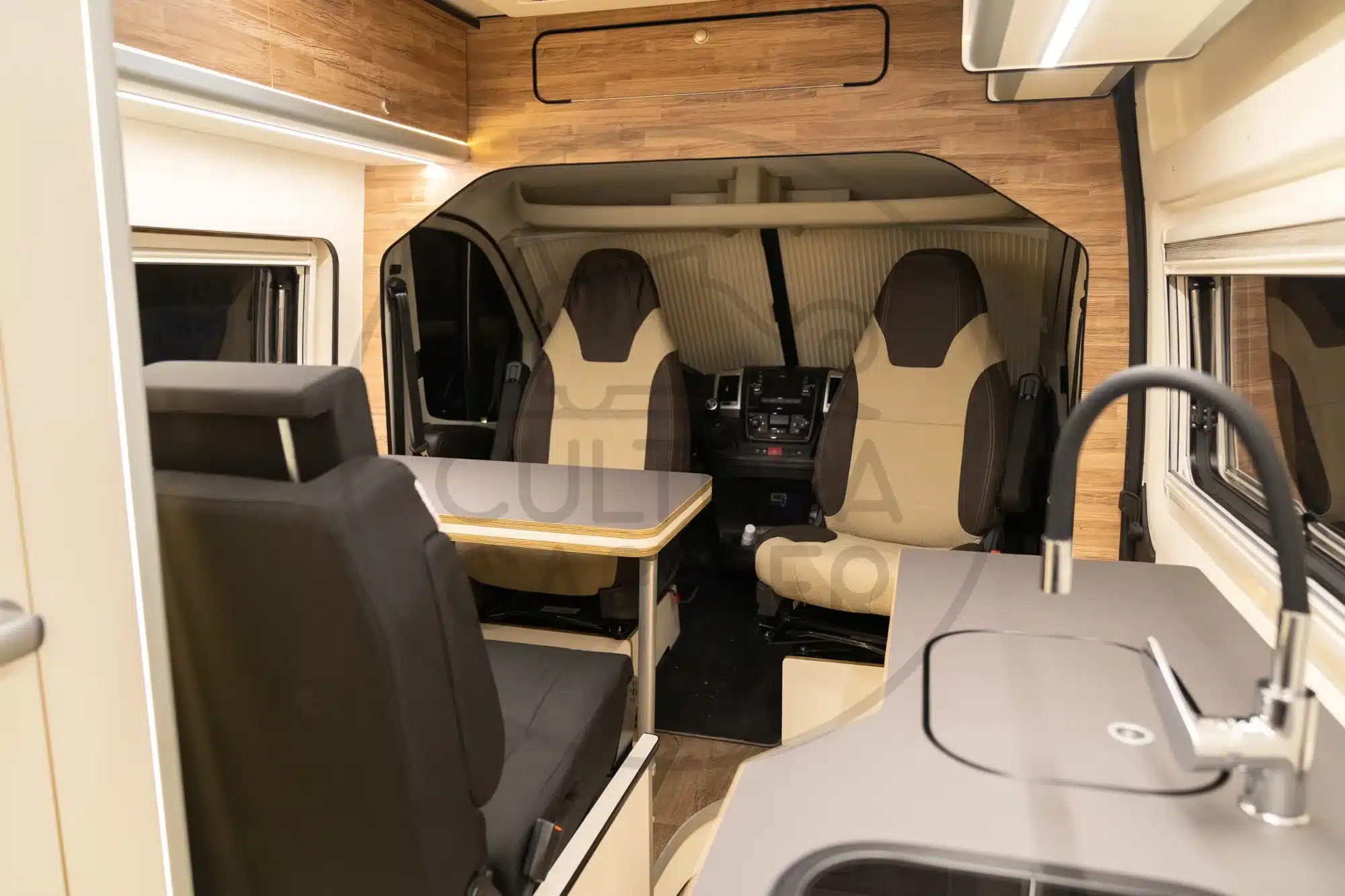 Wohnbereich und Küche eines modern ausgebauten Ducato L4H2 Campervans mit drehbaren Sitzen und Tisch