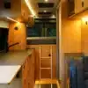Moderner Innenraum des Exploration Vans Codo Campervans mit Küchenzeile, Stauraum und Schlafbereich.