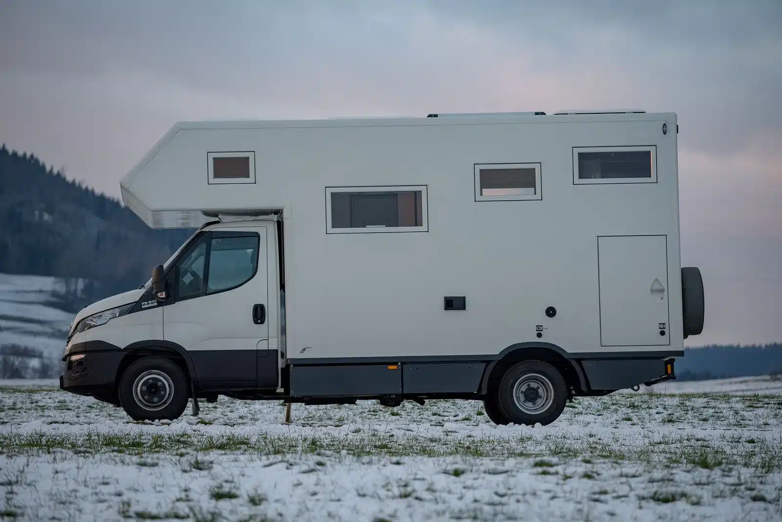 Seitliche Ansicht eines Exploryx Eland Expeditionsmobils auf Basis eines Iveco Daily, geparkt auf verschneitem Feld.
