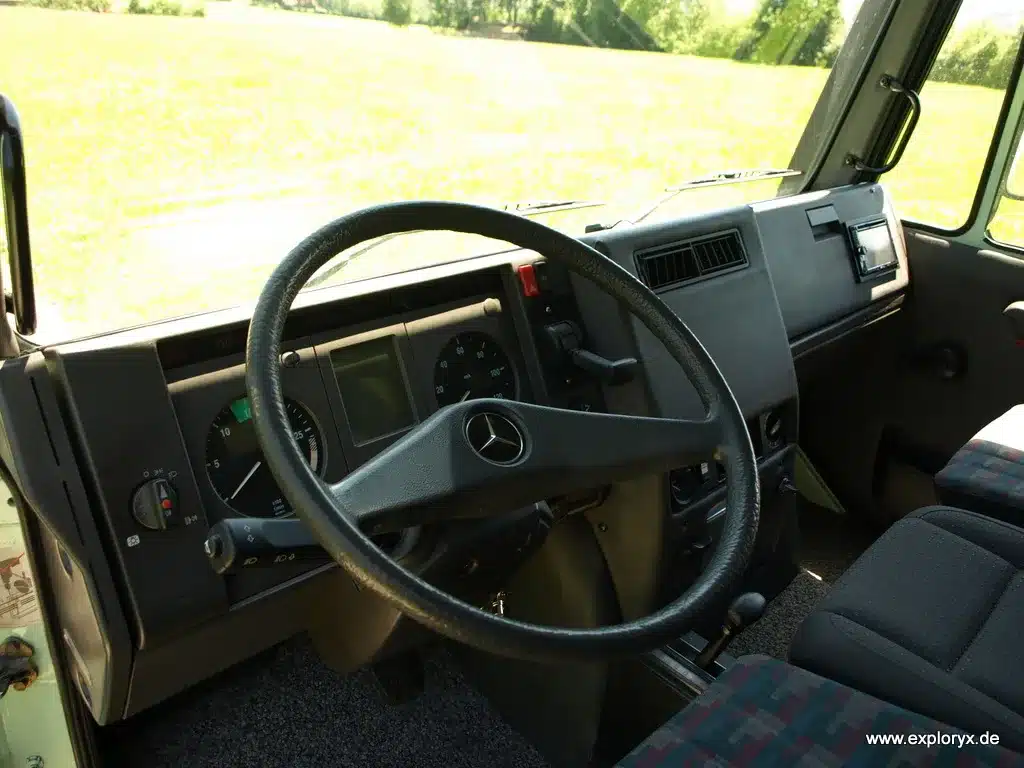 Innenansicht Fahrerhaus eines restaurierten Mercedes-Benz Unimog U140L mit Lenkrad und Armaturenbrett.