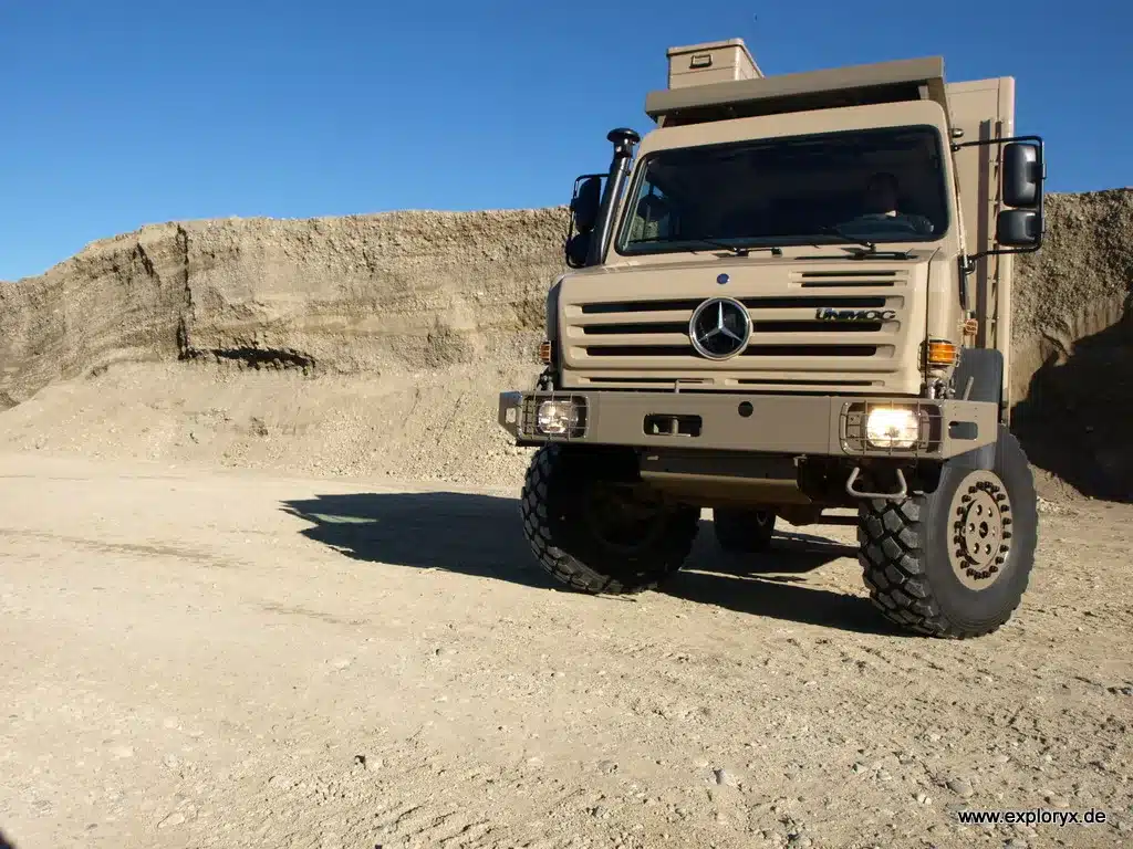 Exploryx Klippspringer U4000, ein Expeditionsmobil auf Unimog-Basis, steht vor einer Felswand im Gelände.
