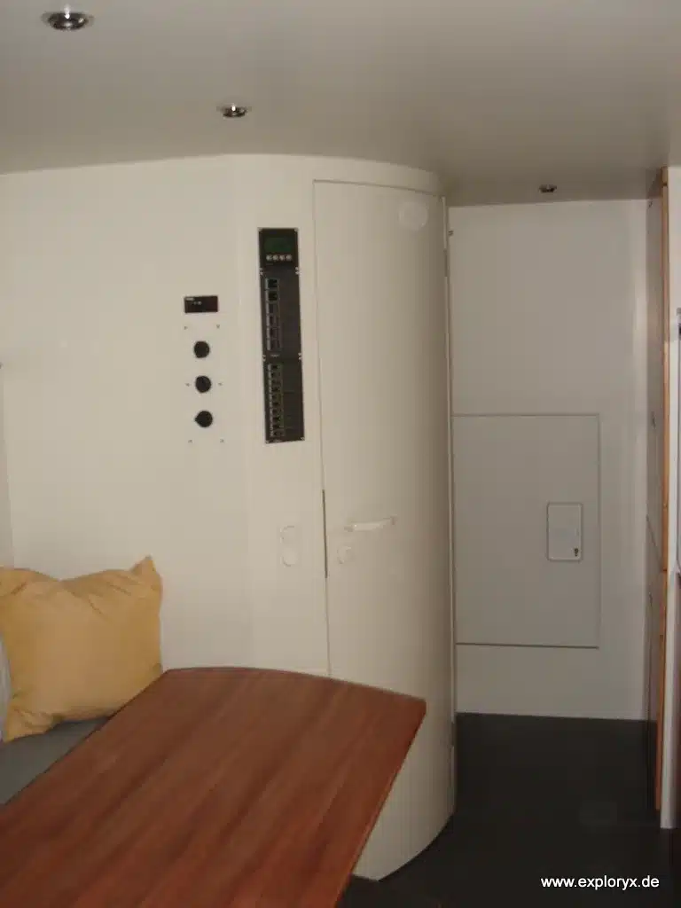 Innenansicht des Wohnbereichs im Exploryx Nyala I auf Mercedes Atego mit Tisch und Technikpanel