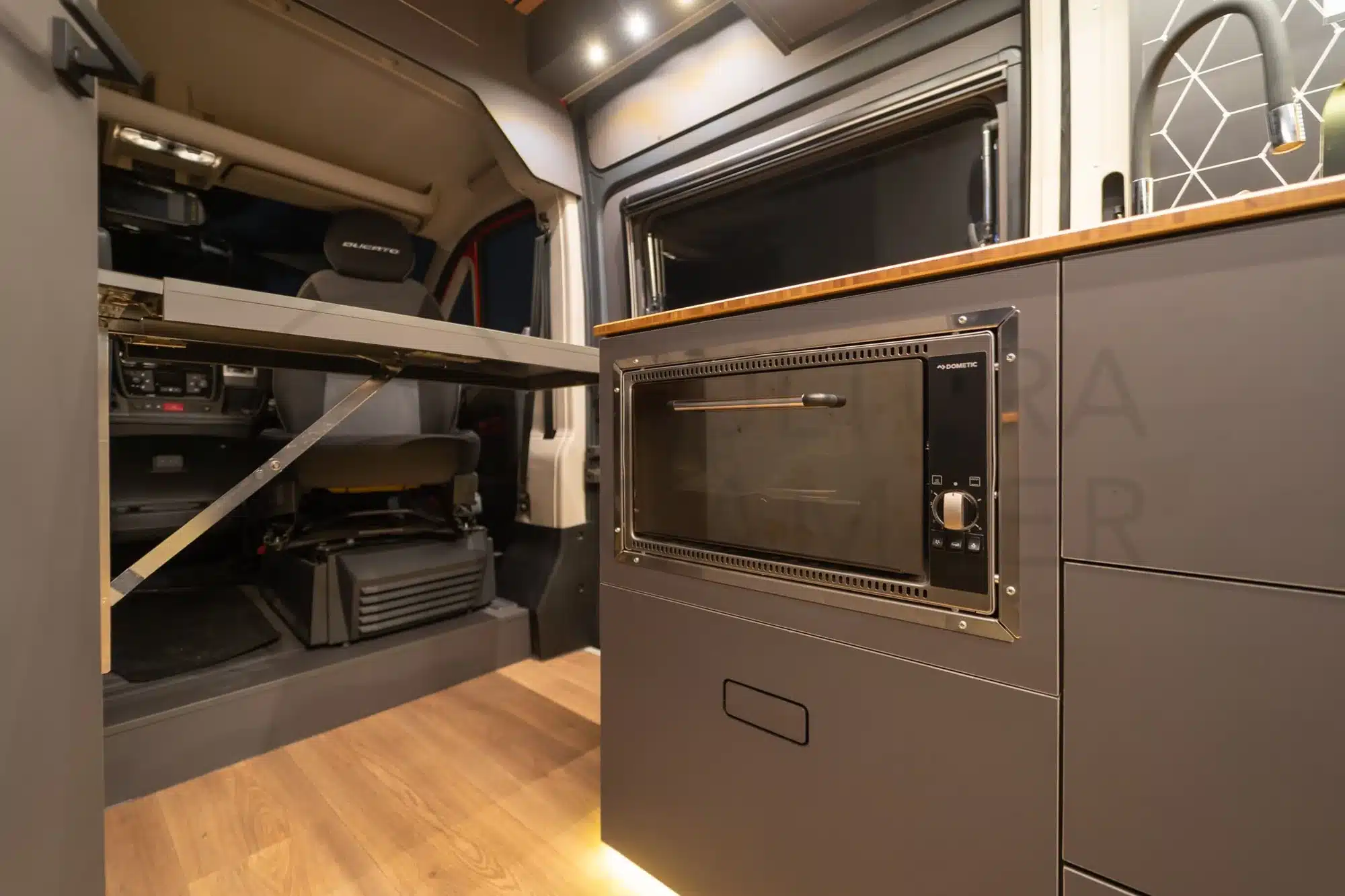 Blick in den Innenraum des Fiat Ducato Oficina Móvil mit Arbeitsplatz und Küchenzeile samt Backofen und Wasserhahn