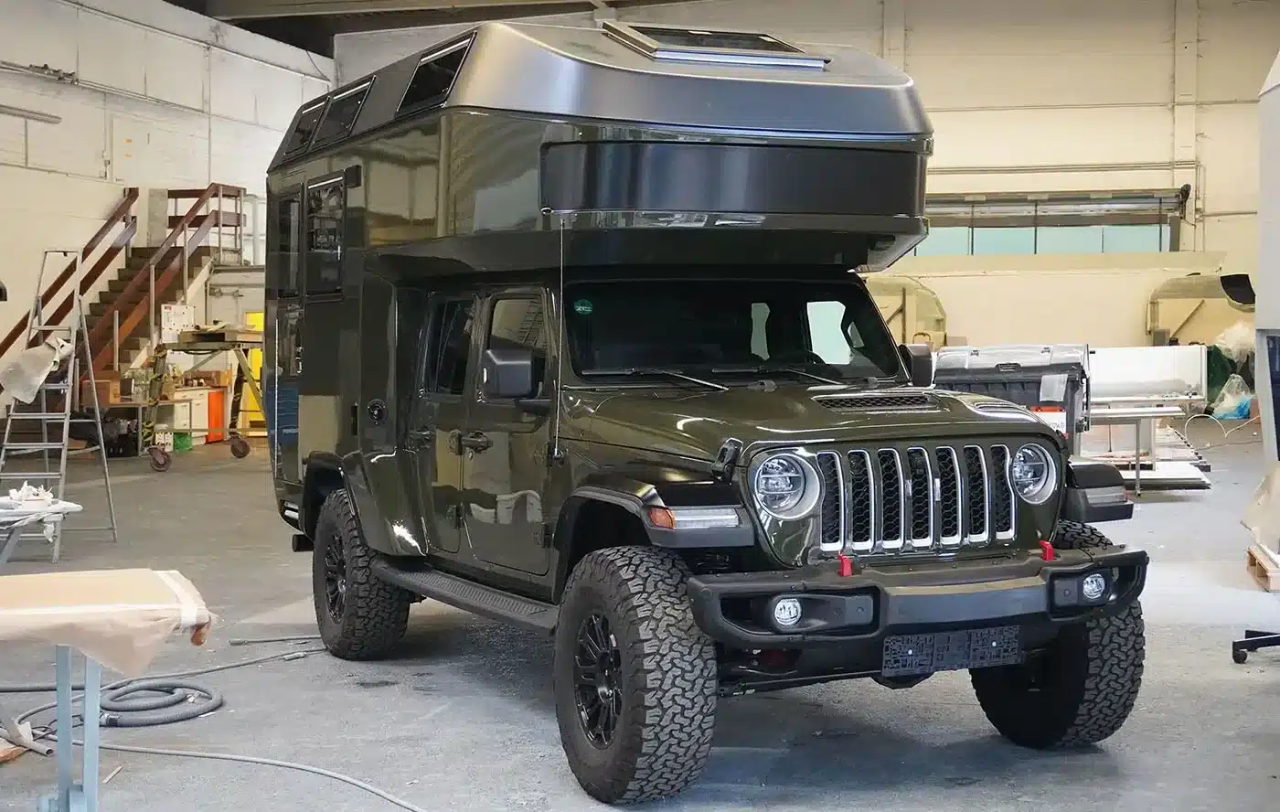 Findus-Wohnkabine montiert auf allradgetriebenem Pick-up, abgestellt in einer Werkstattumgebung.