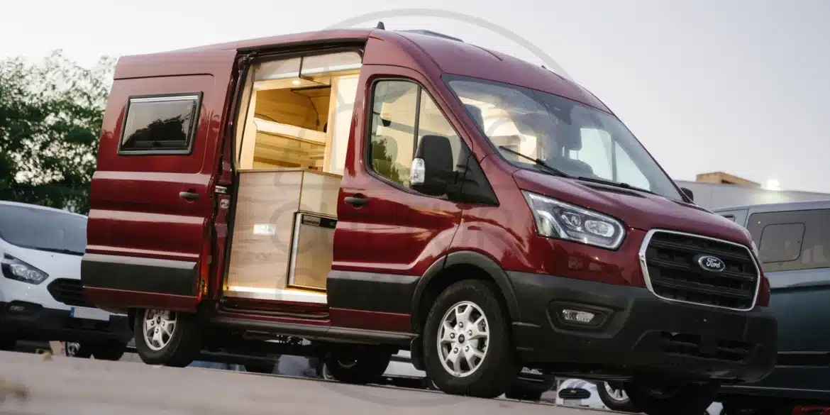 Ford Transit L2H2 Campervan mit offenem Einstieg und individuellem Innenausbau auf einem Parkplatz.
