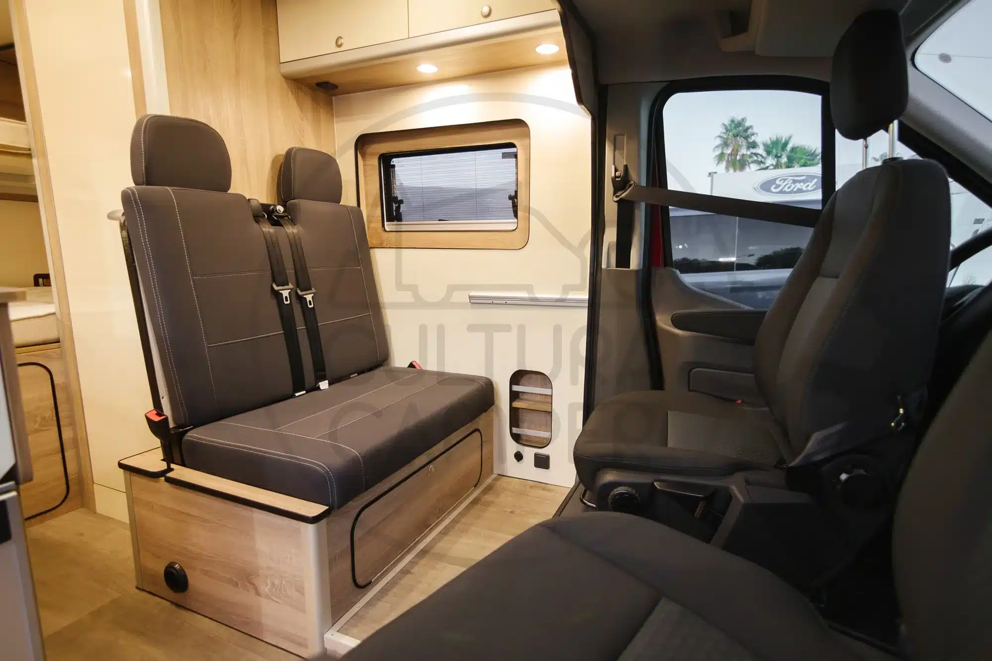 Innenansicht eines ausgebauten Ford Transit L2H2 mit individuell angefertigten Möbeln und Sitzbank.
