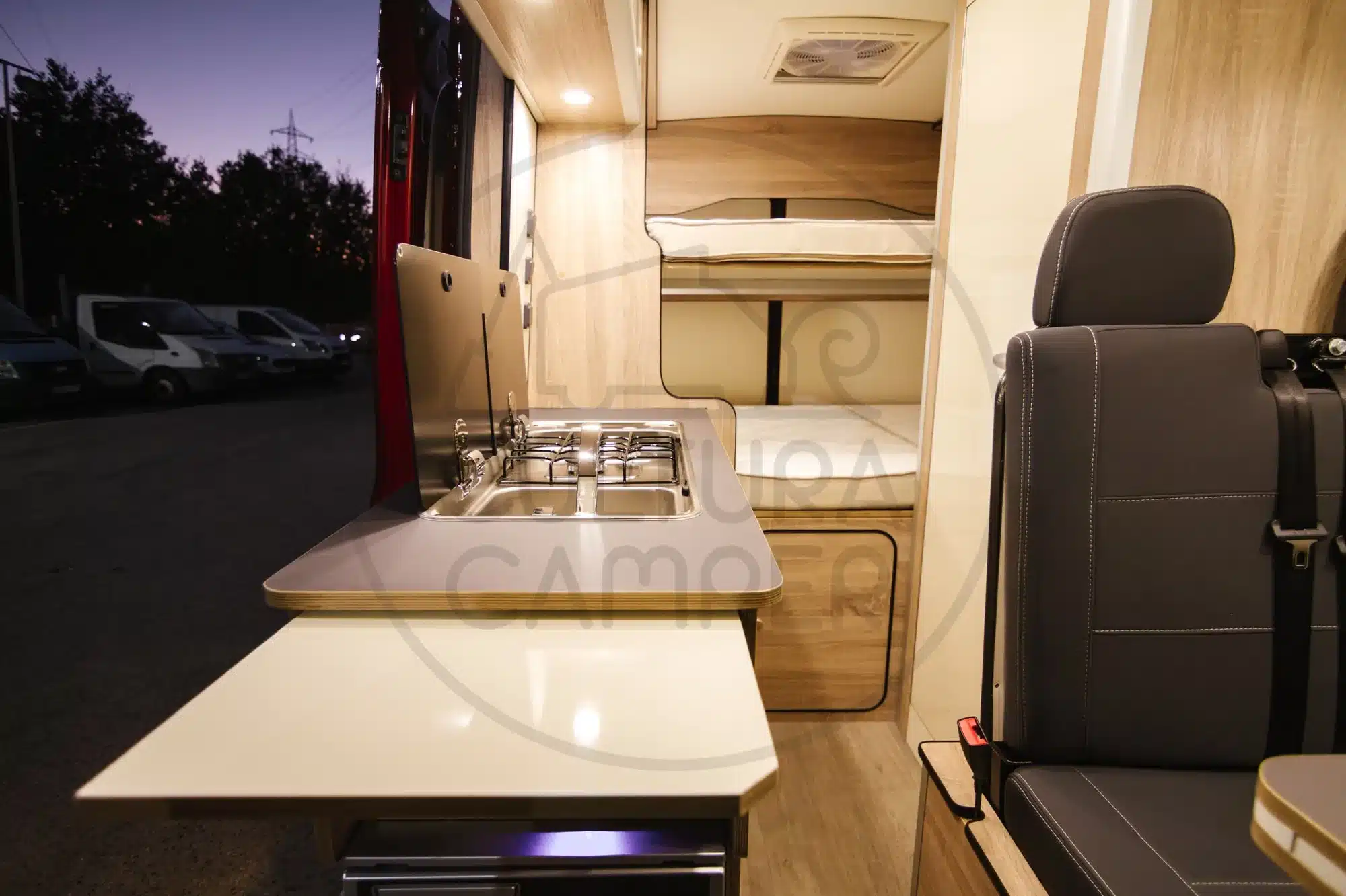 Blick in das Innere eines Ford Transit L2H2 Campers mit maßgefertigter Küche und Schlafbereich