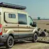 Ford Transit Campervan mit Allradantrieb, Dachträger und ausgebautem Innenraum, geparkt am Sandstrand.