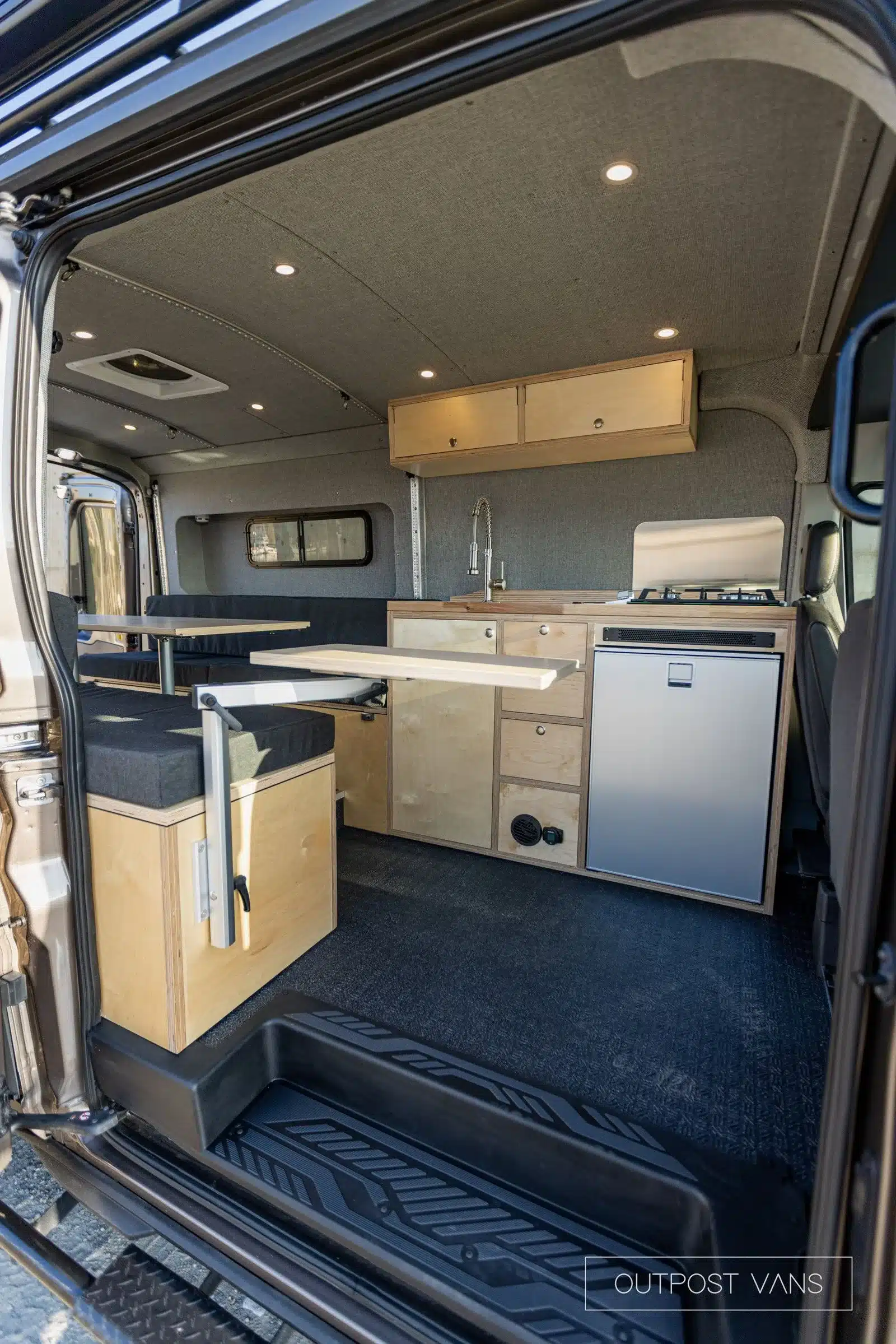 Innenansicht eines Ford Transit Generator Campervans mit Küchenzeile, Sitzgelegenheiten und Klapptischen.