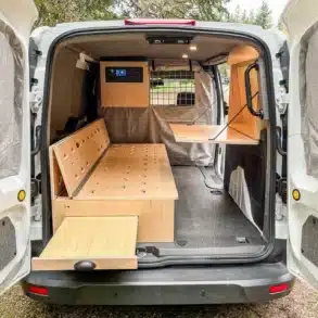 Blick in den Kofferraum eines Ford Transit Connect mit Möbelmodul, Bett und Klapptisch als Camper-Ausbau