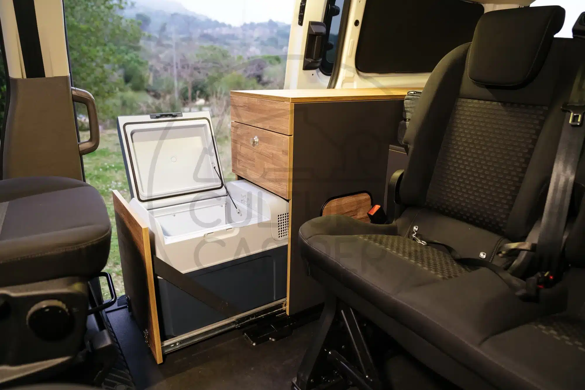 Innenansicht eines Ford Transit Custom Campers mit geöffneter Kompressor-Kühlbox und maßgefertigten Möbeln
