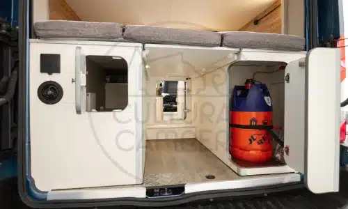 Heckansicht eines Ford Transit L3 H3 Campers mit geöffneten Staufächern und sichtbarer Gasflasche im Innenraum.