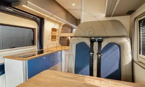 Innenansicht eines ausgebauten Ford Transit L3 H3 Campers mit Sitzplätzen, Tisch und Küche