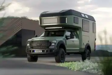 Expeditionsmobil Gehocab Edge Explorer Trail mit 4x4-Antrieb und aufgesetzter Wohnkabine, steht vor einem modernen Gebäude.