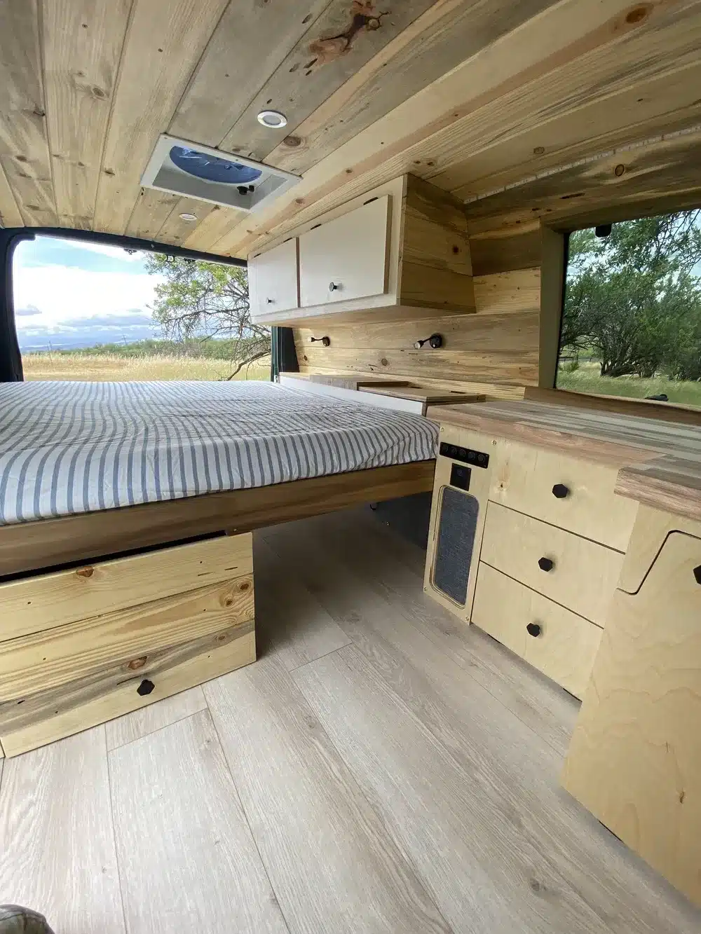 Innenansicht der Green Machine 6AK25 mit Holzverkleidung, Stauraum und festem Bett.