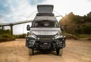 Frontansicht eines silbernen Iveco Daily 4x4 Expeditionscampers mit Offroad-Umbau, aufgestellt auf einer Schotterpiste, Aufstelldach geöffnet.